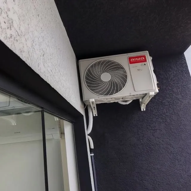 Condensadora instalada em suporte na parede externa, com a tubulação acabada